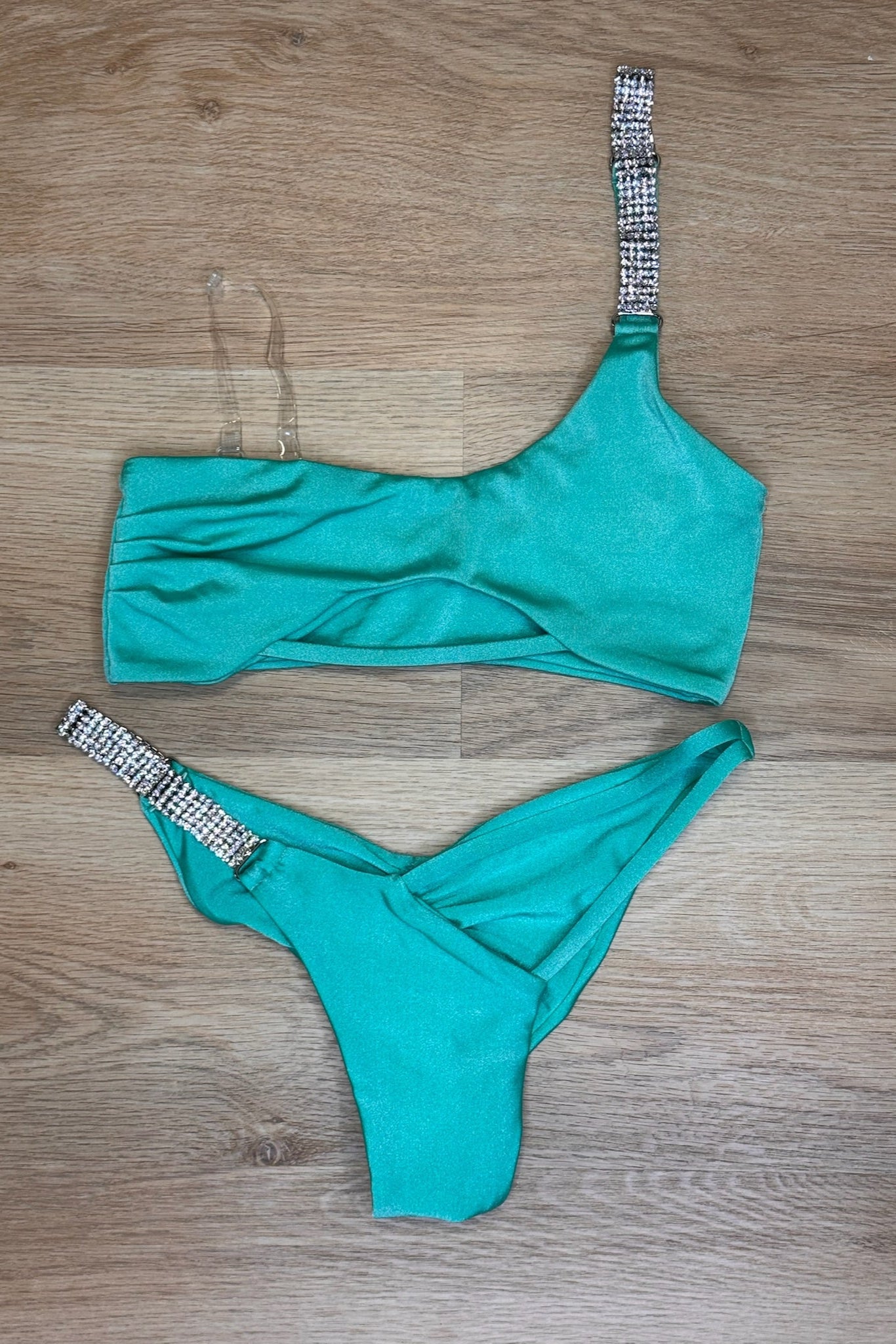 Teal bikini set with crystal details on a wooden floor