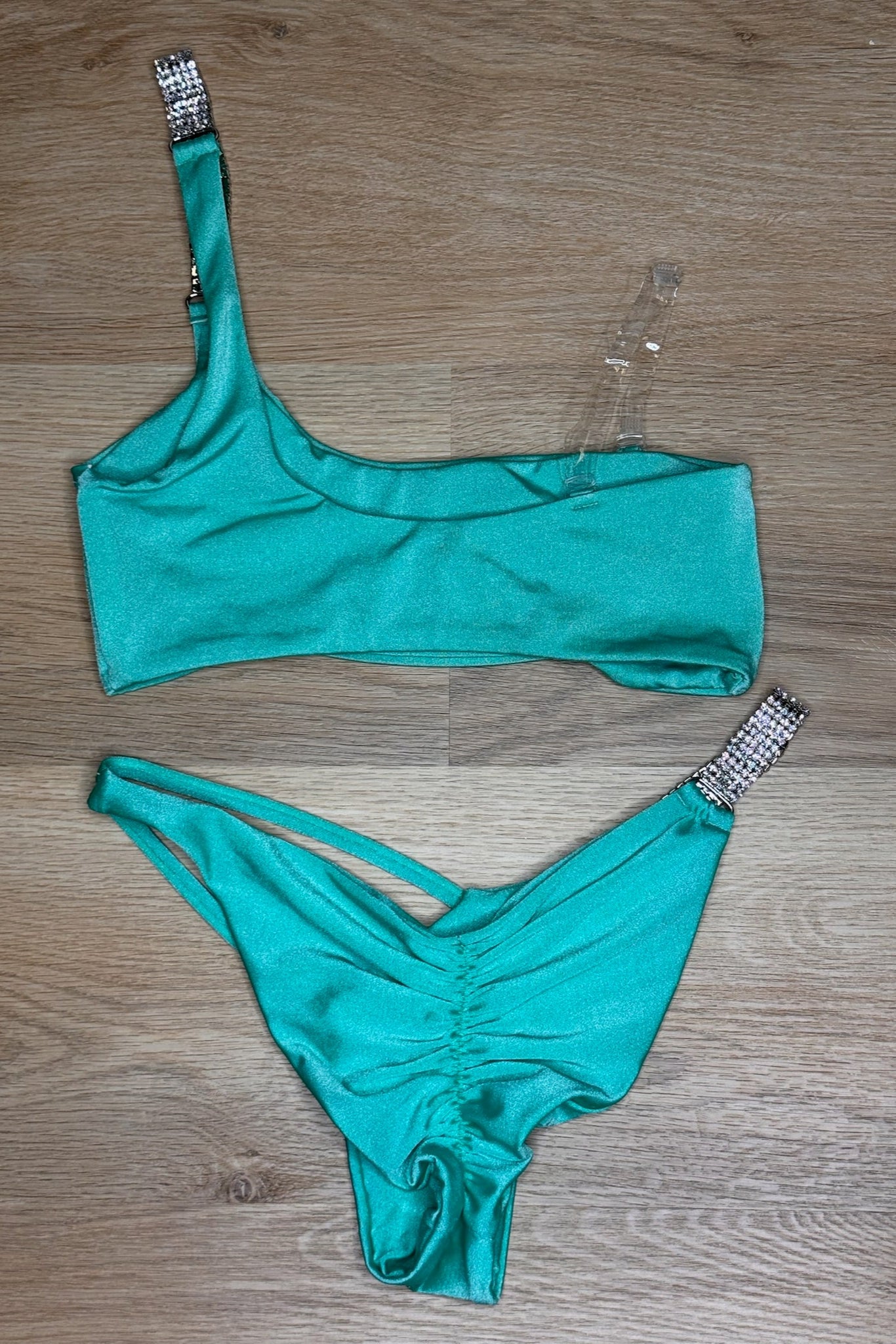 Teal bikini set with rhinestone details on a wooden surface