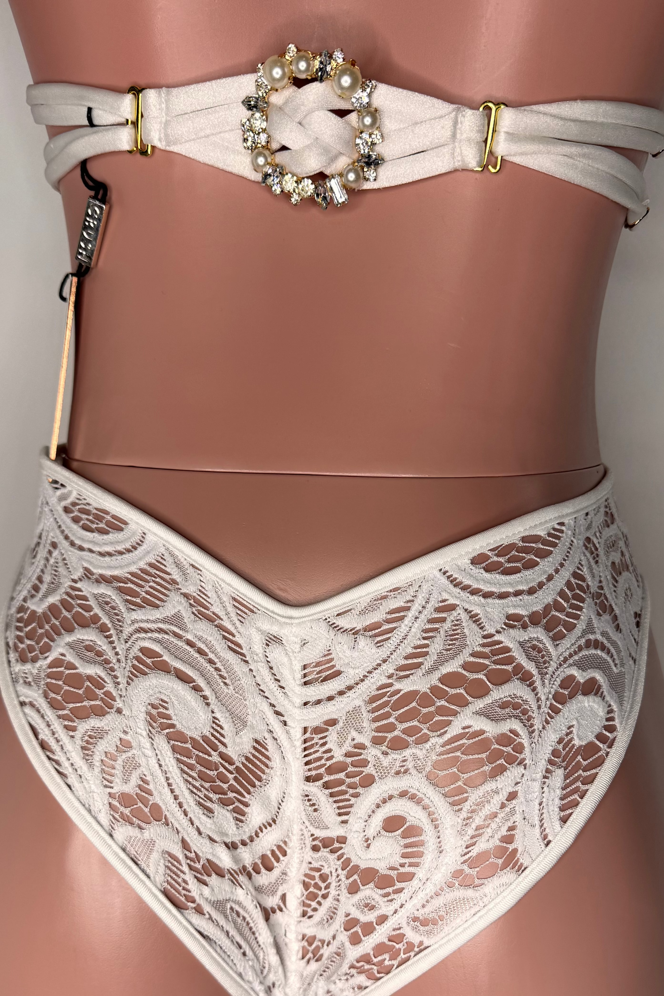 White lace lingerie set with a decorative belt on a neutral background