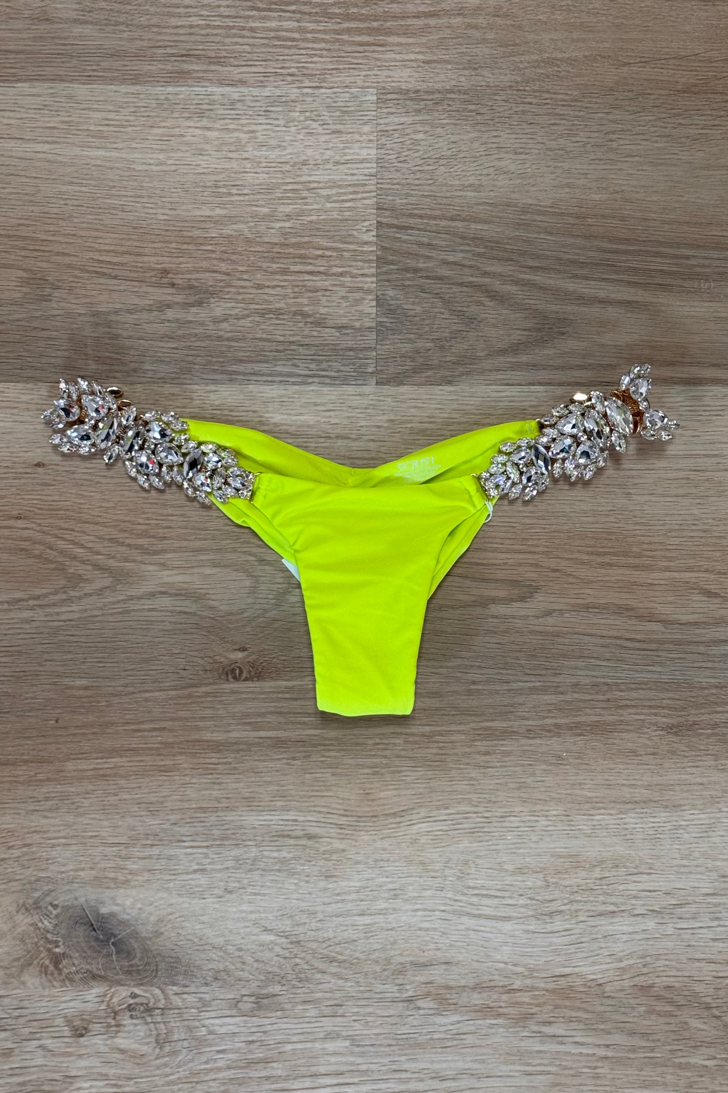 Neon green bikini bottom with embellishments on a wooden surface