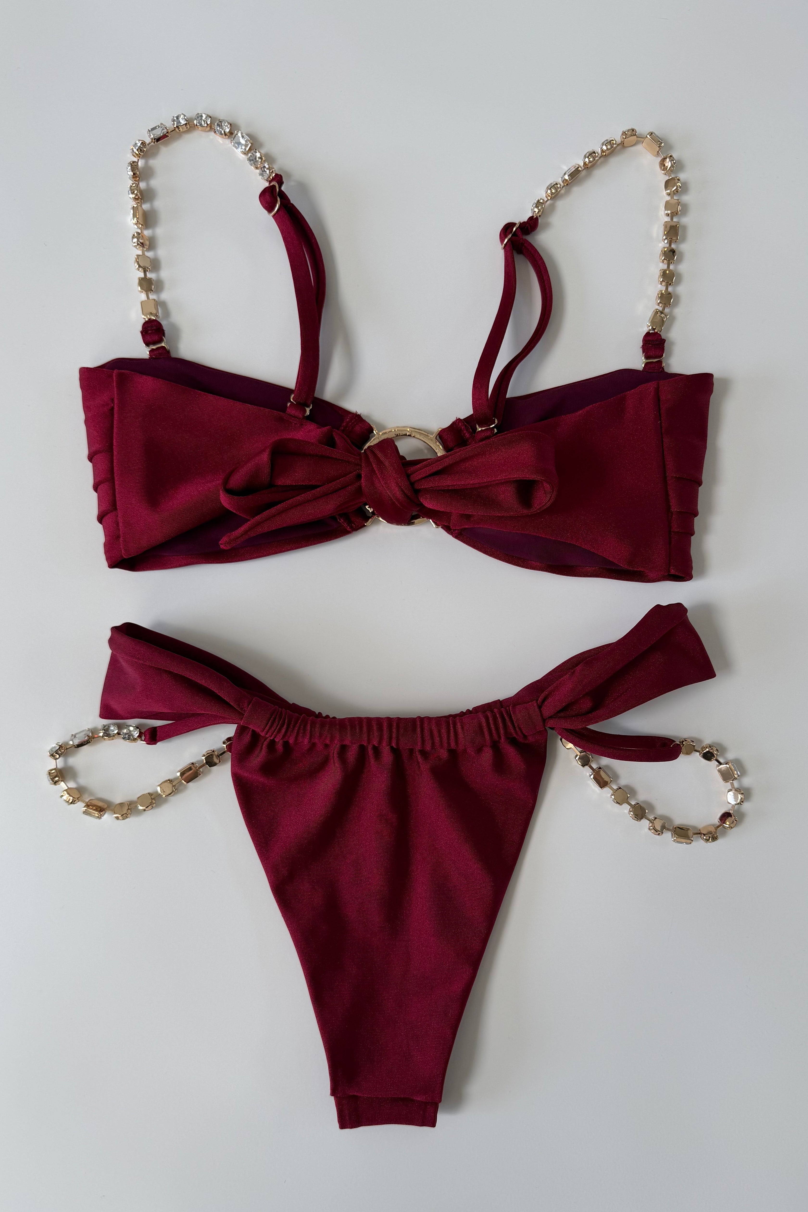 Burgundy satin lingerie set with chain details on a white background