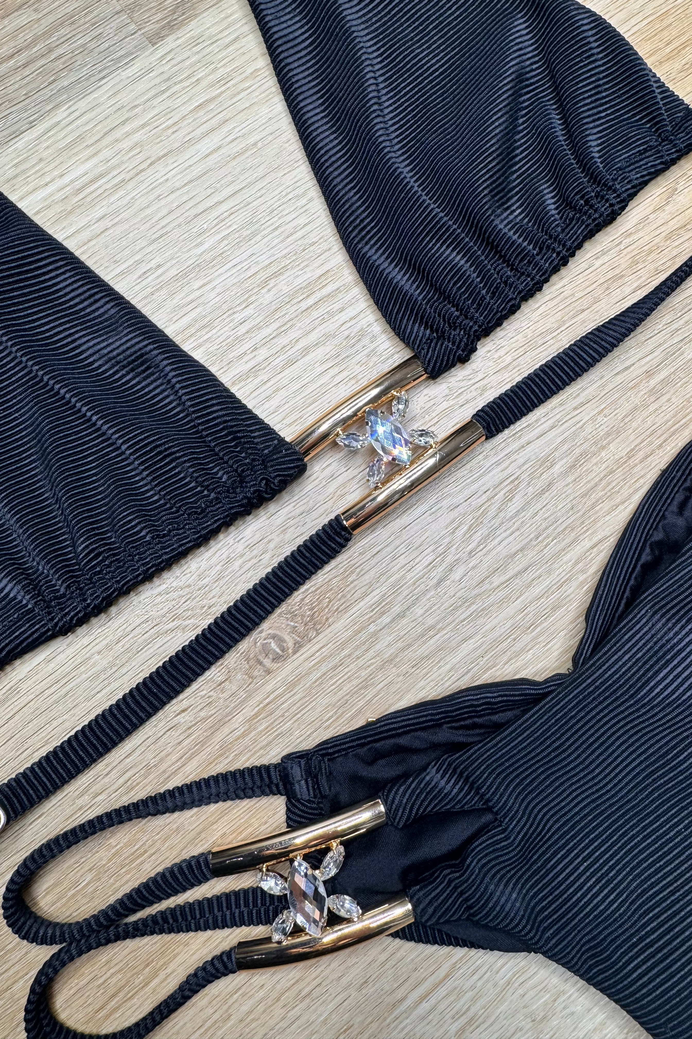 Navy blue bikini set with gold and crystal embellishments on a light wooden surface